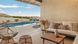 Un área de piscina con un sofá, sillas y una mesa.