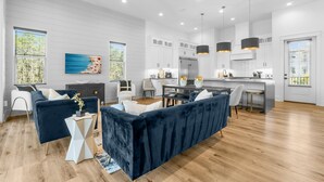 A modern kitchen with white cabinetry, a dining area with a dark blue sofa, and a large window with blinds. - 7-bedroom/ 7-bathroom house; Private pool; Golf cart included (Santa Rosa Beach)