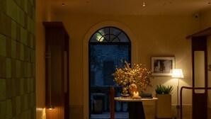 A warmly lit hallway with a large arched doorway, a round table with a candle, and a potted plant. - Golden Age Hotel (Chengdu)
