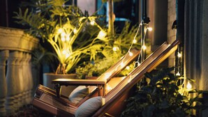 A hammock chair with cushions, surrounded by potted plants and string lights. - Golden Age Hotel (Chengdu)