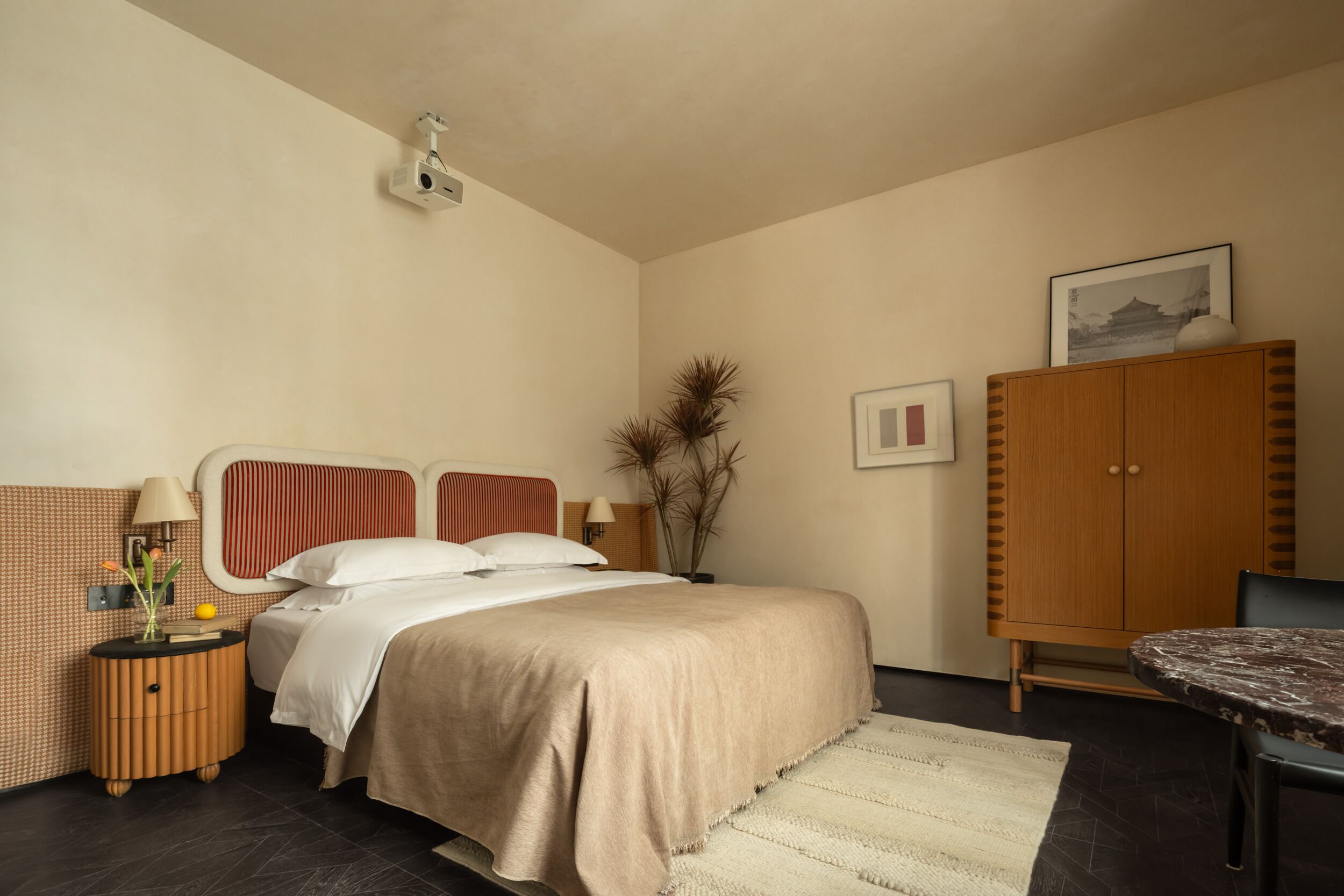 Een slaapkamer met een bed, nachtkastje, lamp en een houten kast.