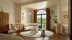 A modern living room with a round coffee table, a white sofa, and a dining table with chairs. - Golden Age Hotel (Chengdu)