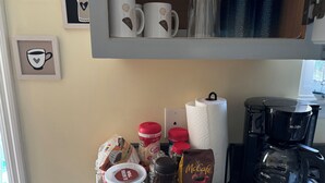 Un comptoir de cuisine avec tout l’équipement nécessaire pour préparer du café, notamment une machine à café de la marque Mr. Coffee, un bocal de café Nescafé Classic et un paquet de café McCafé Premium Roast.