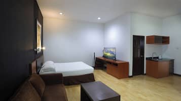 Una habitación de hotel compacta con una cama, un sofá, un escritorio con televisor y una kitchenette.