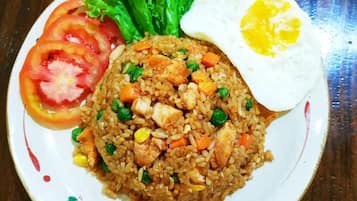 Un plato de arroz frito con verduras y un huevo frito, servido en un plato con estampado floral.
