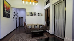 Una sala de estar con sofá, mesa de centro, alfombra estampada y cuadros en la pared.