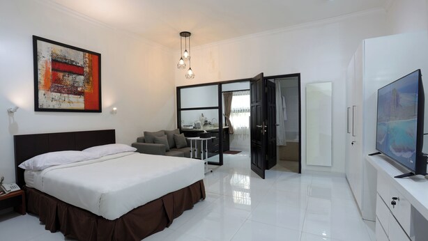 Una habitación de hotel moderna con una cama grande, una televisión de pantalla plana, un escritorio y un sofá.