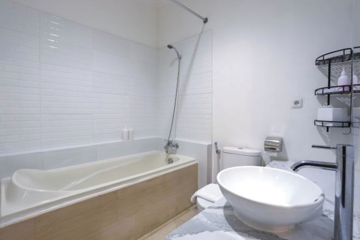 A modern bathroom with a bathtub, a freestanding sink, and a toilet.