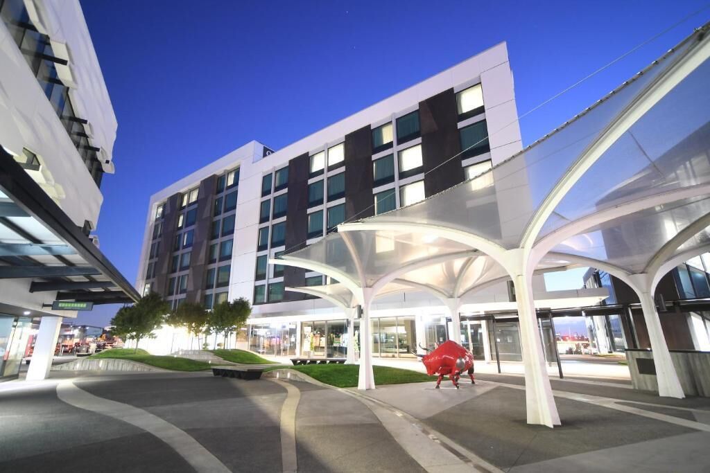 A modern building with a covered entrance and a red sculpture.