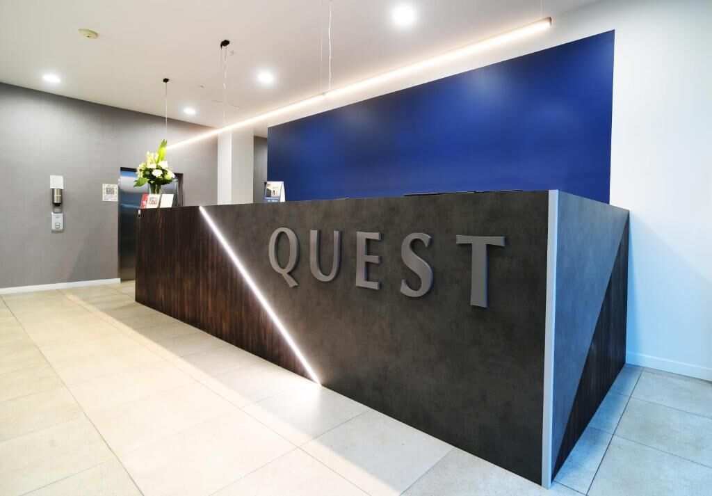 A reception desk with the word "QUEST" prominently displayed.