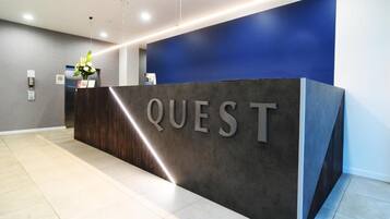 A reception desk with the word "QUEST" prominently displayed.