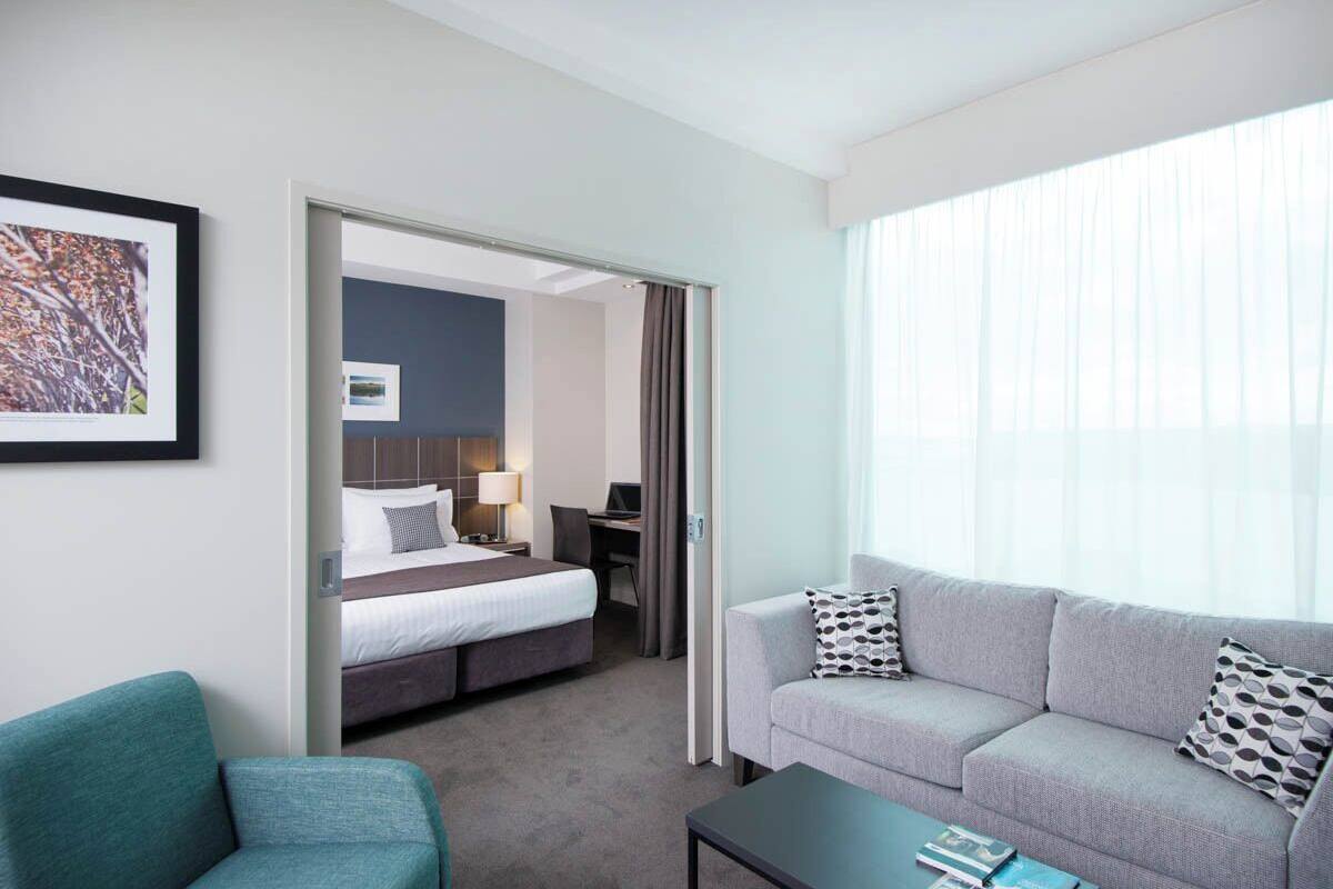 Habitación de hotel con cama, escritorio, sofá y mesa de centro.