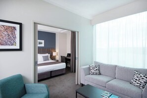 A hotel room with a bed, a desk, a sofa, and a coffee table.