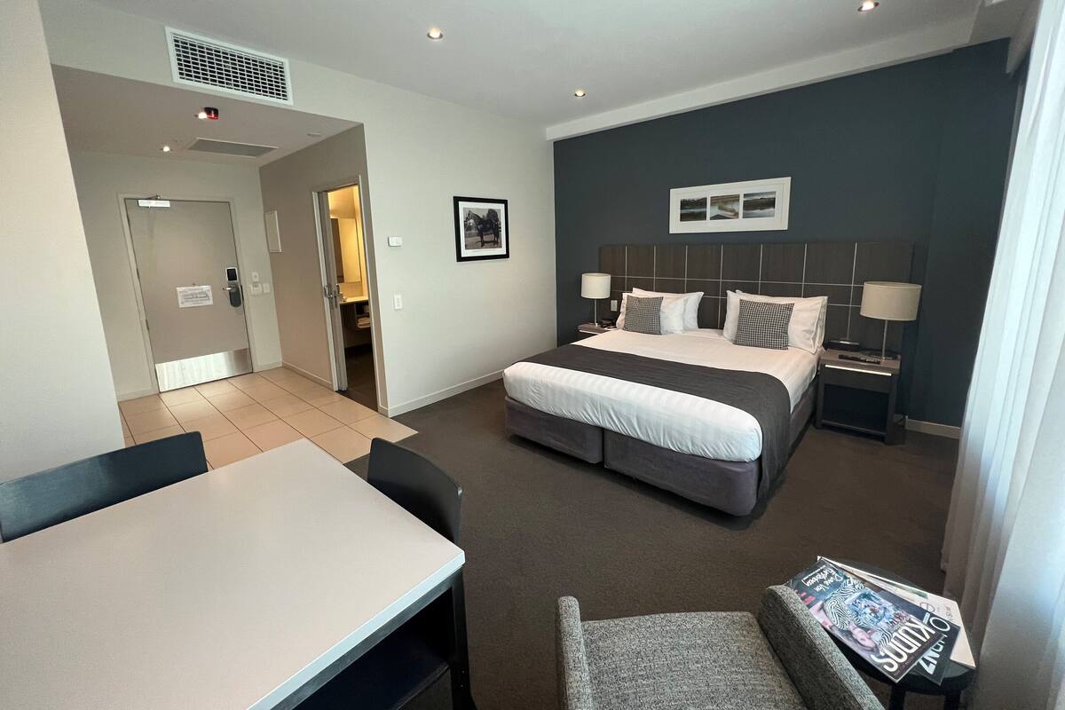Una habitación de hotel con una cama, mesitas de noche, un escritorio y una silla.