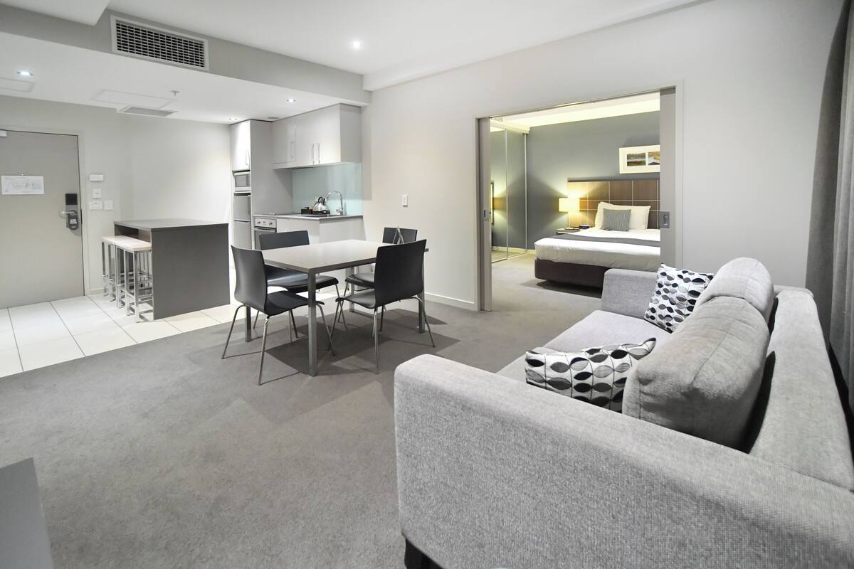 Un apartamento moderno con comedor, kitchenette y un dormitorio con cama y mesita de noche.
