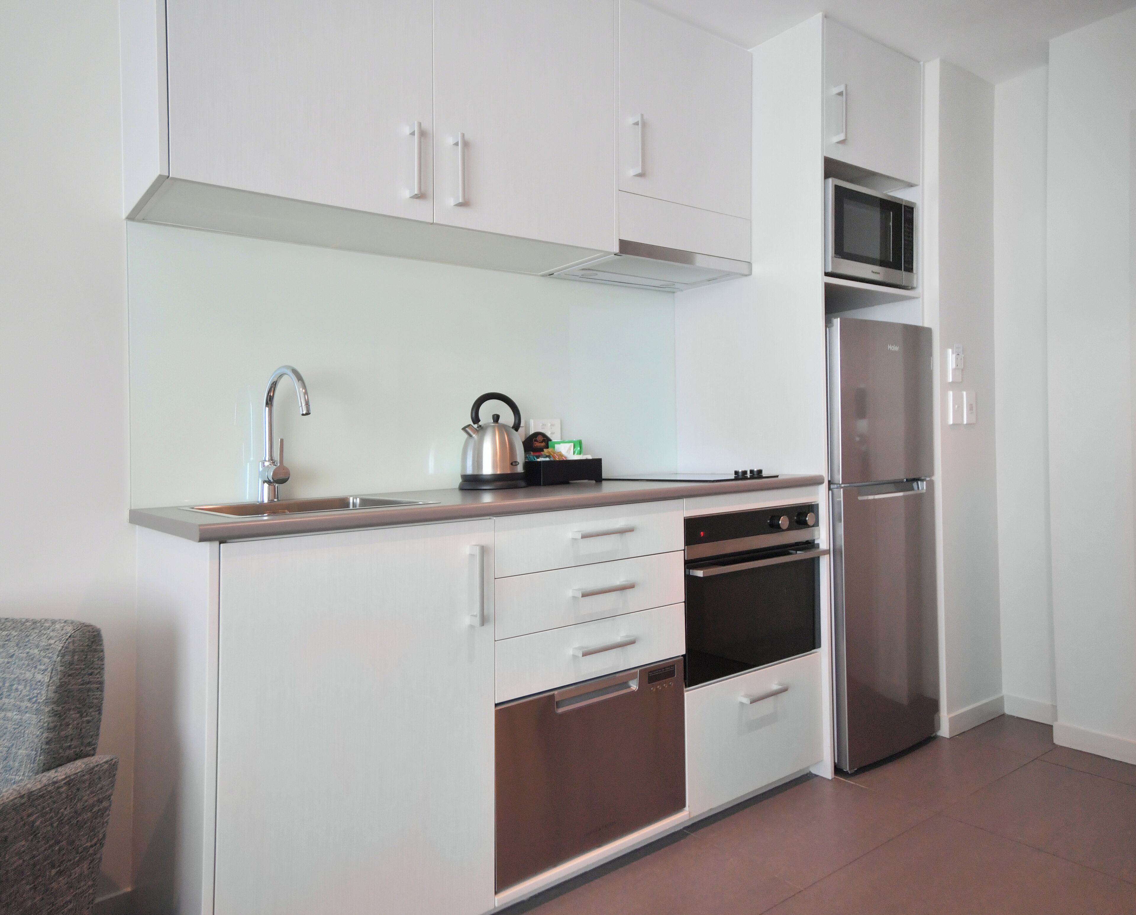 A modern kitchen with white cabinets, stainless steel appliances, and a built-in oven.