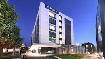 Un hotel moderno con fachada plana, ventanas amplias y un llamativo letrero con el nombre "QUEST".