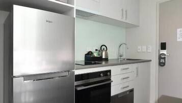 Una cocina moderna con electrodomésticos de acero inoxidable, armarios blancos y horno empotrado.