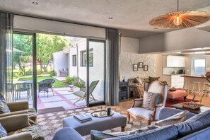 Un salon moderne doté d’une grande porte-fenêtre coulissante donnant sur une terrasse, un coin cuisine et un espace repas.