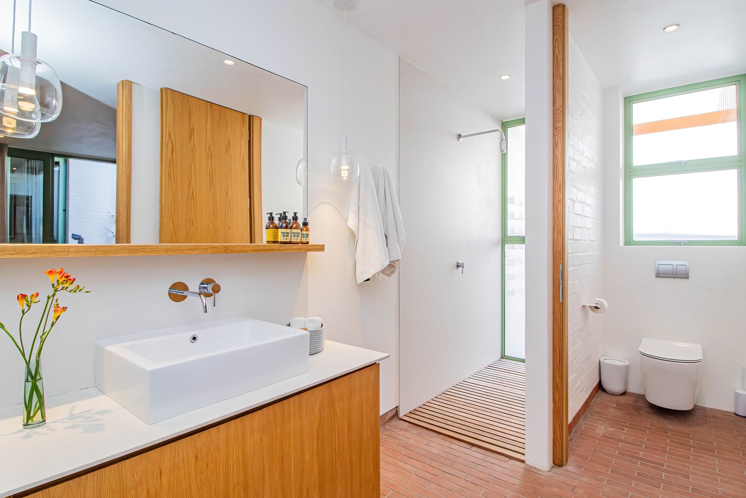 A modern bathroom with a white sink, wooden vanity, and a large mirror.