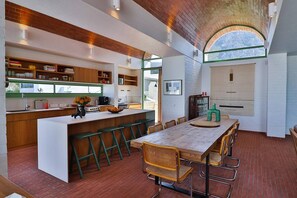 A modern kitchen with a central island, bar stools, and a dining table with chairs.