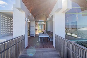 A modern outdoor patio with a wooden deck, a dining table, and a seating area.