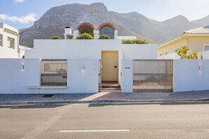 A modern building with a white facade, a wooden door, and a gated entrance.