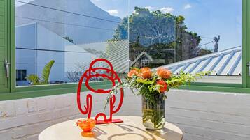 Une table ornée d’un vase de fleurs et d’une sculpture abstraite rouge.