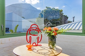 A table with a vase of flowers and a red abstract sculpture.
