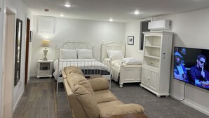 A bedroom with a bed, two bedside tables, a TV, a sofa, and a wardrobe.