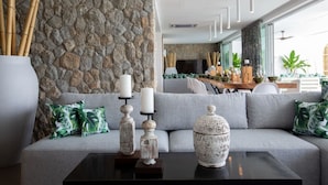 Un salon moderne avec un mur en pierre, un canapé gris et des objets décoratifs disposés sur une table basse.