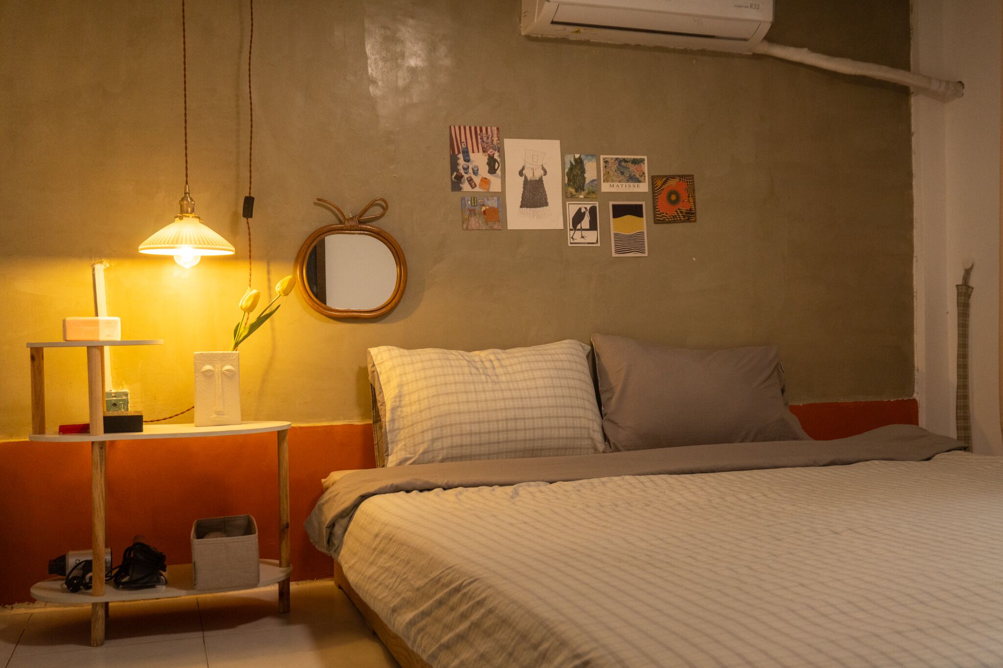 A bedroom with a bed, a bedside table with a lamp, a mirror, and wall art.