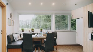 A modern kitchen with a wooden dining table, black chairs, and a built-in oven.