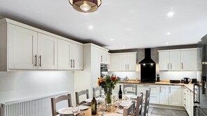 A modern kitchen with white cabinetry, a central island, and a dining area set for six.