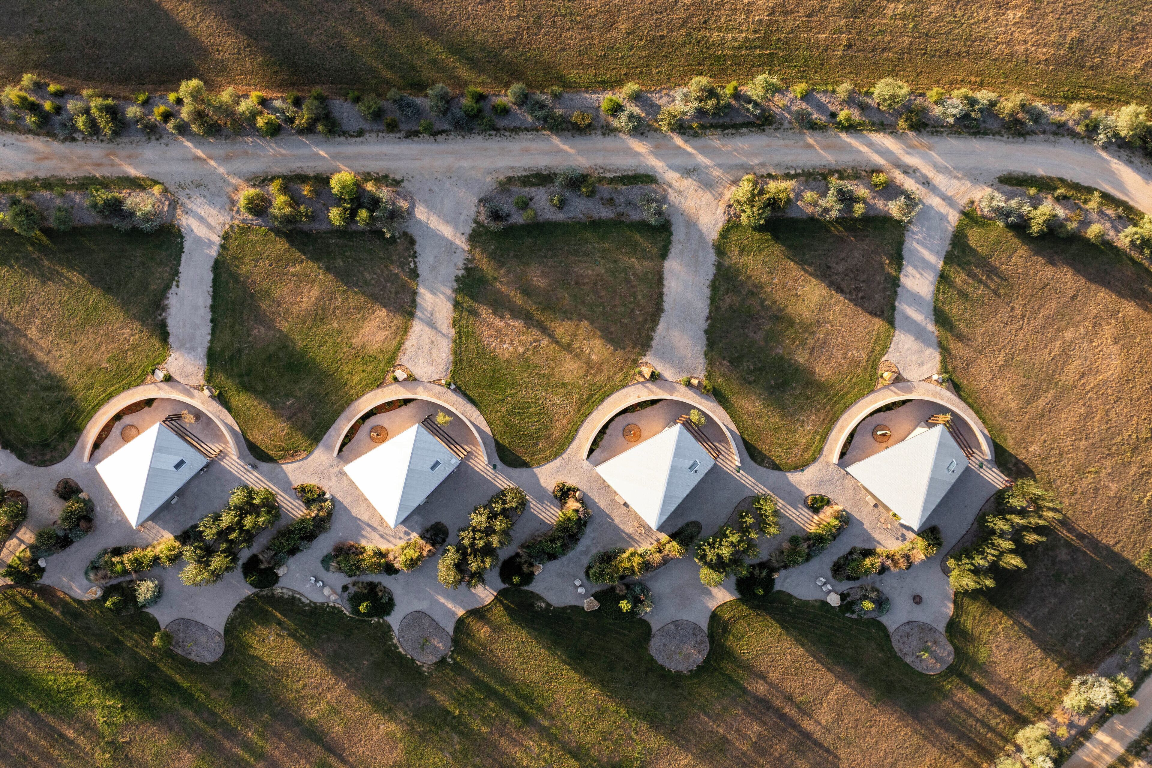 Luchtbeeld van een bezit met drie afzonderlijke gebouwen, elk met een centrale binnenplaats en omringd door aangelegde tuinen.