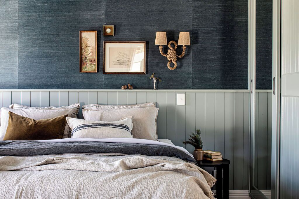 A bedroom with a bed, two wall-mounted lamps, and two framed pictures.