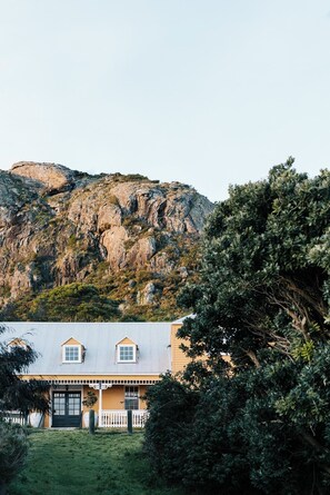 A house with a gabled roof, a front porch, and a view of a rocky mountain.