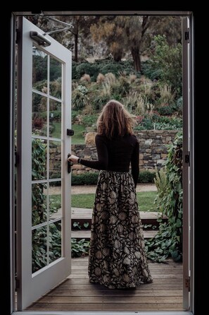 A woman standing at an open door with a view of a garden.