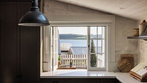 A kitchen with a large window overlooking a deck and water. - Ship Inn Stanley (Stanley)