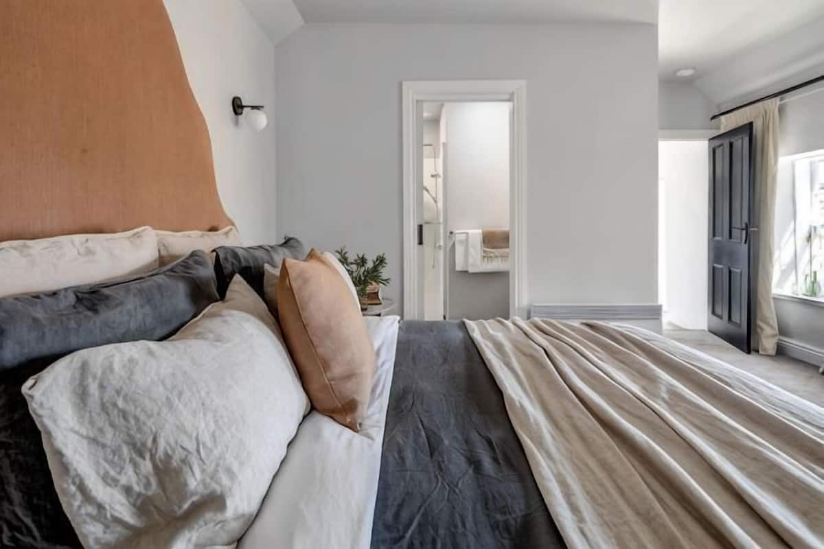 A bedroom with a bed, a door, and a window.