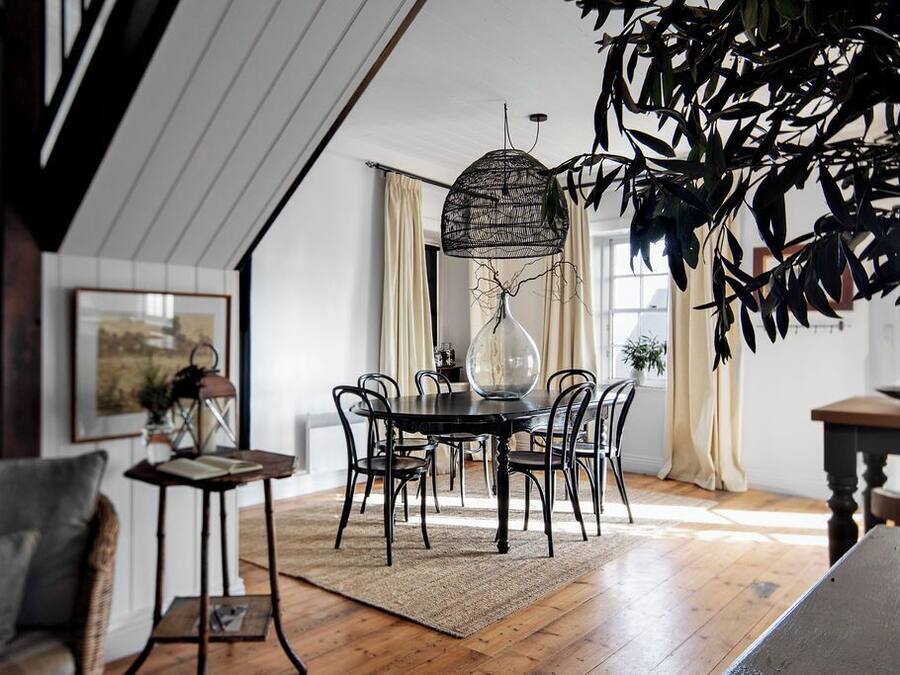 A dining area with a round table, black chairs, and a hanging light fixture.