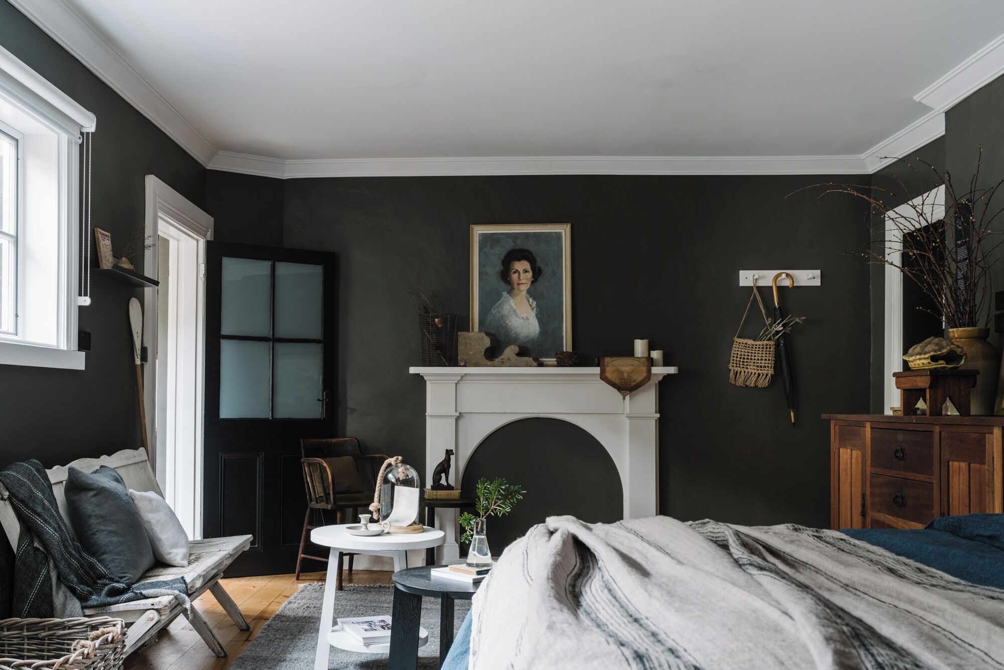 A room with a fireplace, a painting, a wooden cabinet, and a window.
