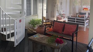 A covered outdoor area with a wooden staircase, seating, and potted plants.