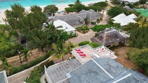 A coastal resort with multiple bungalow-style buildings, a beach, and a central patio area with outdoor seating.