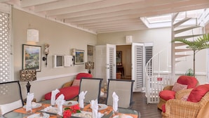 A dining area with a table set for four, a wicker sofa, and a staircase leading to an upper level.