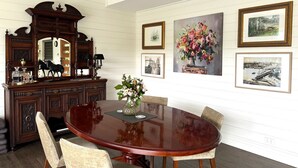 A dining room with a large wooden table, chairs, a decorative mirror, and framed artwork on the walls. - Grand View Luxury Villa (Kangaroo Valley)