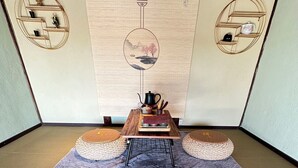 Une pièce avec un sol recouvert de tatamis, une petite table basse, des coussins et un service à thé japonais traditionnel.