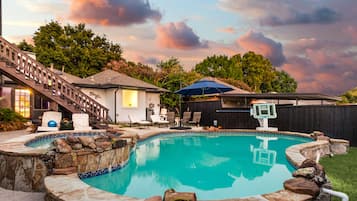 A backyard with a swimming pool, a basketball hoop, and a staircase leading to a house.