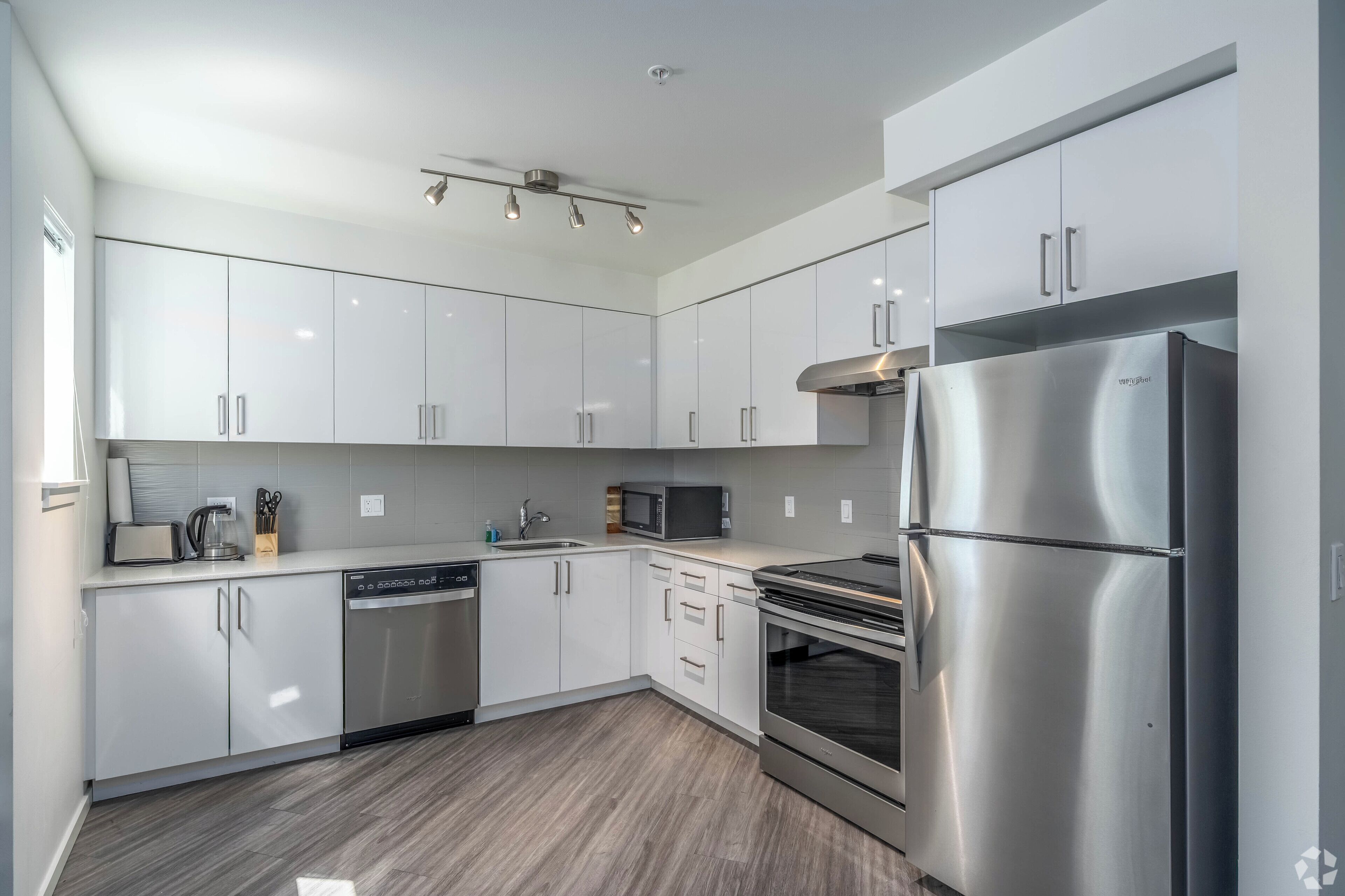 A modern kitchen with white cabinets, stainless steel appliances, and a built-in oven.