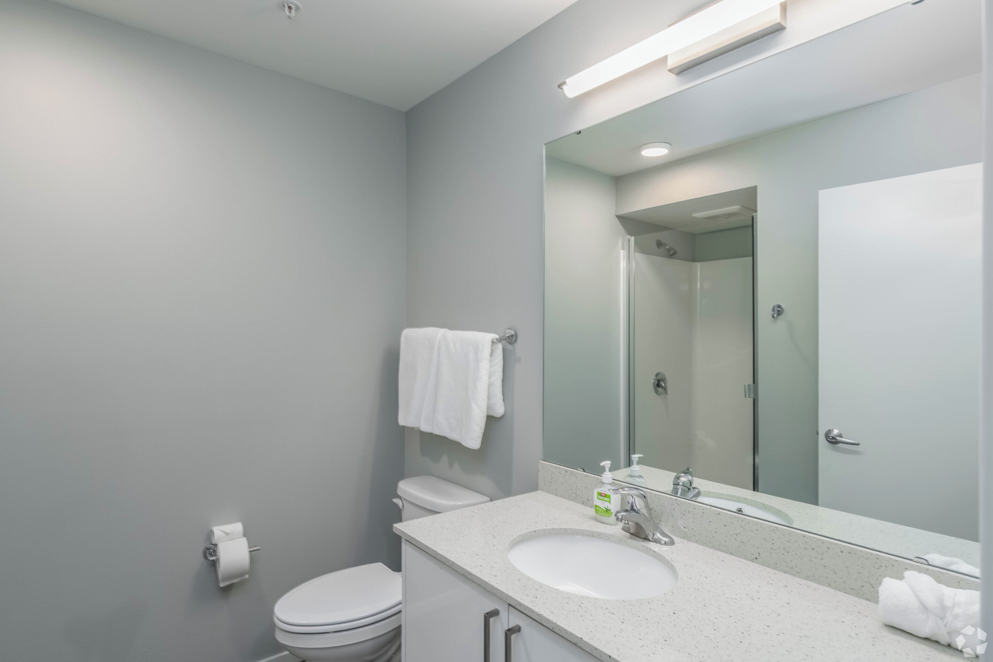 Un baño moderno con lavamanos, espejo y retrete blancos.